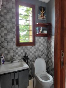 a bathroom with a toilet and a sink and a window at Funvilla Family House in Dar es Salaam