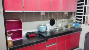 a small kitchen with red cabinets and a sink at Homestay Hafiy Manjung Lekir Sitiawan 