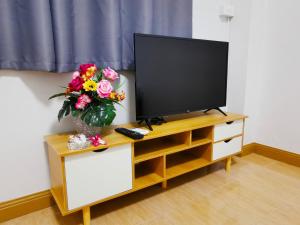 a tv on a cabinet with a vase of flowers at Fall Asleep hotel in Nonthaburi