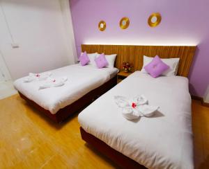 two beds in a room with pink and white pillows at Fall Asleep hotel in Nonthaburi