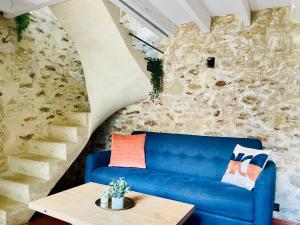 a blue couch in a room with a stone wall at Maisonette duplex - Tout equipé - Matelas haute qualité in Marly-le-Roi