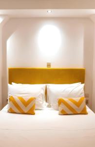 a bed with yellow and white pillows on it at Apeiron Acropolis Suites in Athens