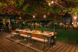 a long table with chairs in a garden at night at Lutyens Bungalow in New Delhi