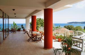 eine Veranda mit roten Säulen und Stühlen und Meerblick in der Unterkunft Maranton Beach Hotel in Kinira