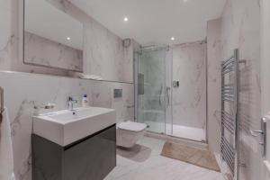a bathroom with a sink and a shower and a toilet at Harley Street Spectacular Suites with High Ceilings, High Luxury in London