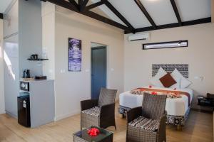 a bedroom with a bed and chairs in a room at Seatiki Resort Fiji On Coast in Sigatoka