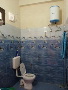 ein Bad mit einem WC mit Delfinen an der Wand in der Unterkunft KAUSHALYADHAM MUNSYARI in Munsyari