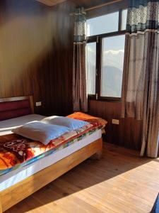 ein Schlafzimmer mit einem Bett und einem großen Fenster in der Unterkunft KAUSHALYADHAM MUNSYARI in Munsyari