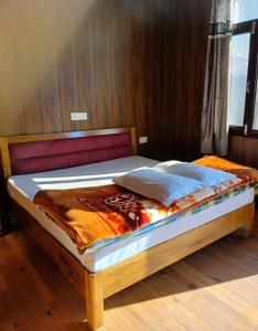 ein Bett mit einem Holzrahmen in einem Zimmer in der Unterkunft KAUSHALYADHAM MUNSYARI in Munsyari