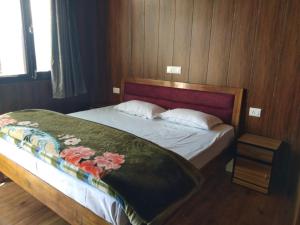 ein Schlafzimmer mit einem Bett mit einer Blumendecke darauf in der Unterkunft KAUSHALYADHAM MUNSYARI in Munsyari