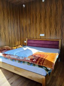 ein Schlafzimmer mit einem Bett mit einer Holzwand in der Unterkunft KAUSHALYADHAM MUNSYARI in Munsyari