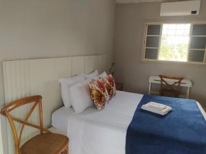 een slaapkamer met een bed en 2 stoelen en een raam bij Recanto do Turista in Chapada dos Guimarães