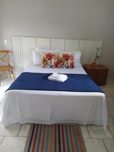 een groot wit bed met een blauwe deken en kussens bij Recanto do Turista in Chapada dos Guimarães