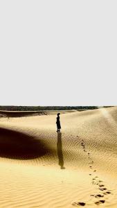 Une personne qui marche dans le sable dans le désert dans l'établissement Marigold Homestay, à Jaisalmer