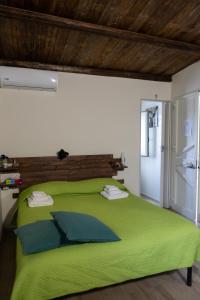 Filuvespri في كوميزو: غرفة نوم مع سرير أخضر مع اللوح الأمامي الخشبي