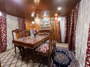 a dining room with a wooden table and chairs at Houseboat wild rose in Srinagar