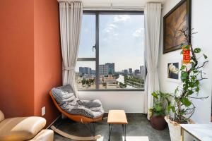 a living room with a chair and a large window at Olala SaiGon Apartment - Millennium Tower in Ho Chi Minh City