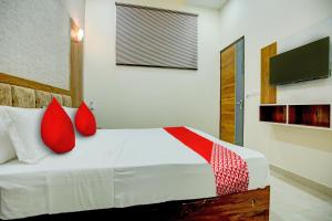 a bedroom with a bed with red pillows and a tv at Flagship Hotel Elista in Zirakpur