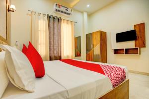 a bedroom with a bed with red pillows and a tv at Super OYO Flagship Hotel Elista in Zirakpur