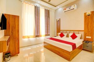 a bedroom with a bed with red pillows and a television at Super OYO Flagship Hotel Elista in Zirakpur
