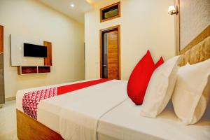 a bedroom with a bed with red and white pillows at Flagship Hotel Elista in Zirakpur
