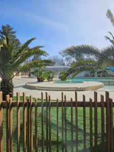 a wooden fence in front of a park with palm trees at Vacances en Mobil home à Piriac sur mer in Piriac-sur-Mer