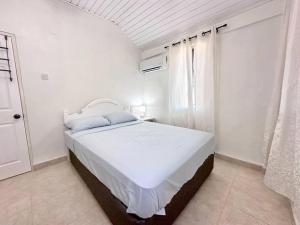 a white bedroom with a large bed and a window at Beach Walk in Saint James