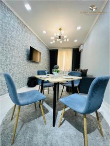 une salle à manger avec des chaises bleues et une table dans l'établissement Comfortable 2-roomed apartment Ozod Apartments, à Samarcande
