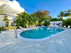 une grande piscine avec des chaises et des arbres dans l'établissement 12 Foursquare Rockley Golf & Country Club, à Bridgetown