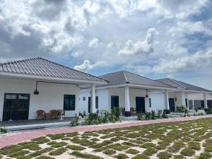 une maison blanche avec une pelouse devant elle dans l'établissement Ocean Cottage 2, Radiant Teluk Sari, à Kampung Mawar