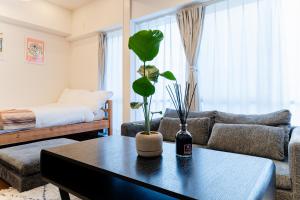 a living room with a couch and a table with a plant at SAKURA Residence目黒駅前 Standard in Tokyo