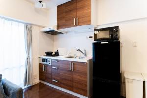 a small kitchen with wooden cabinets and a black refrigerator at SAKURA Residence目黒駅前 in Tokyo