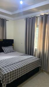 a bedroom with a bed with a checkered blanket on it at Eden Meadows Estate (Dr. John) in Limbe