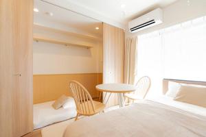1 dormitorio con 1 cama, mesa y sillas en unito residence HIKAWADAI, en Tokio