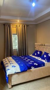 a bed with blue and white sheets and a window at Eden Meadows Estate (Dr. John) in Limbe