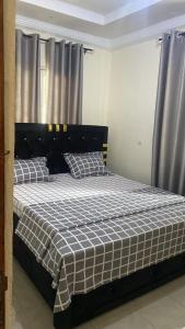 um quarto com uma cama com um cobertor xadrez em Eden Meadows Estate (Dr. John) em Limbe