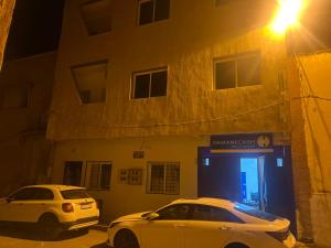 dwa samochody zaparkowane w nocy przed garażem w obiekcie Appartement 6 meublée 2 étage w mieście Wadżda