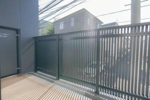 una valla metálica con una casa en el fondo en unito residence HIKAWADAI, en Tokio