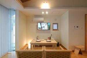 a dining room with a table and a tv on the wall at 駐車場有 琉球モダンと木の暖かさ 陽光が降り注ぐ上品でゆとりのある空間 2階 in Kume