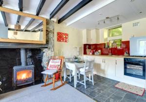 cocina con chimenea, mesa y fogones en Mynydd Annedd Cottage en Beddgelert