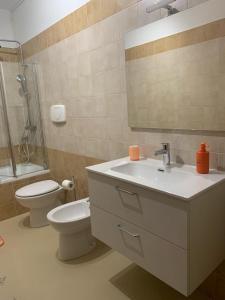 een badkamer met een wastafel, een toilet en een spiegel bij Come Casa Tua in Carovigno