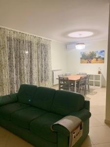 uma sala de estar com um sofá verde e uma mesa em Come Casa Tua em Carovigno