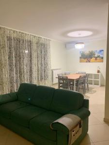 Una sala de estar con un sofá verde y una mesa. en Come Casa Tua, en Carovigno