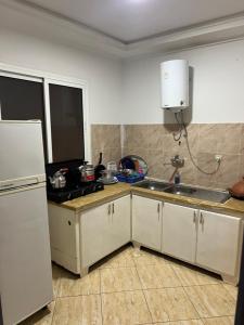eine Küche mit weißen Schränken, einer Spüle und einem Kühlschrank in der Unterkunft Appartement 6 meublée 2 étage in Oujda