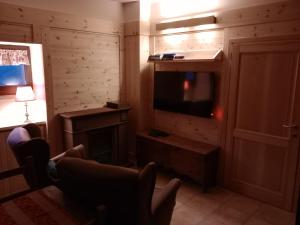 uma sala de estar com uma televisão de ecrã plano e uma cadeira em B&B DELL'ANTICA OSTERIA -Varzo em Varzo