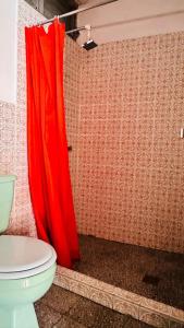 Baño con cortina de ducha roja junto a un aseo en Royal Palace Hostal en Panajachel