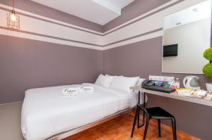 a bedroom with a bed and a desk with a laptop at Fragrance Hotel - Kovan in Singapore