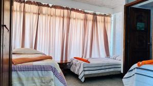 1 Schlafzimmer mit 2 Betten und einem Fenster mit Vorhängen in der Unterkunft Royal Palace Hostal in Panajachel