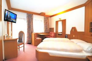 a hotel room with two beds and a flat screen tv at Pension Alpenhof in San Leonardo in Passiria