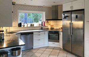 a kitchen with white cabinets and a stainless steel refrigerator at 4 Bedroom Stunning Home In Ljusterö in Norra Ljustero